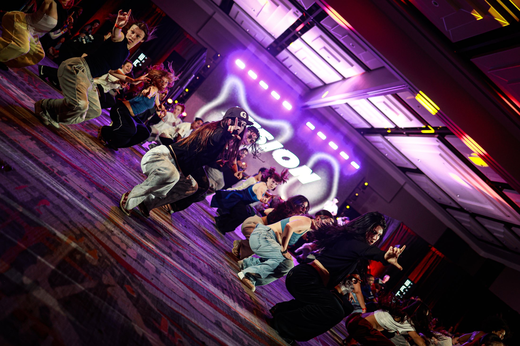 Color-rich dance formation performing in sync with layered stage lighting and crowd energy.